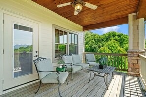 A covered porch with a ceiling fan, a wooden deck, and a seating area with chairs and a table.