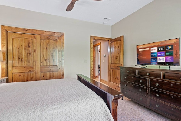 A bedroom with a bed, a dresser, a TV, and wooden doors.