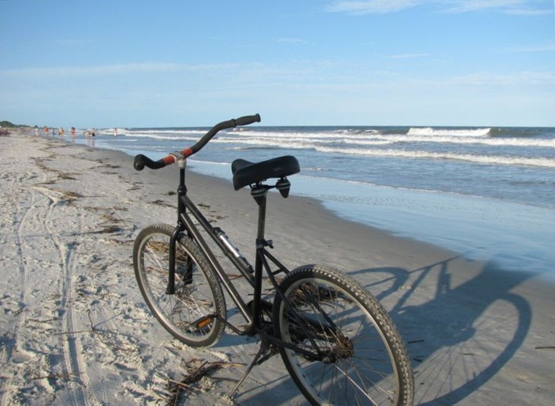 A bicycle parked on a sandy beach with the ocean in the background.