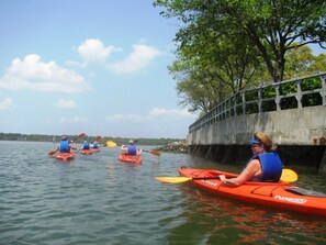 A group of people kayaking on a calm lake, with a concrete bridge and trees in the background. - SUPER VALUE VACATION HOUSE: PRIVATE BEACH, GOLF, POOL, BIKES
 (Hilton Head)