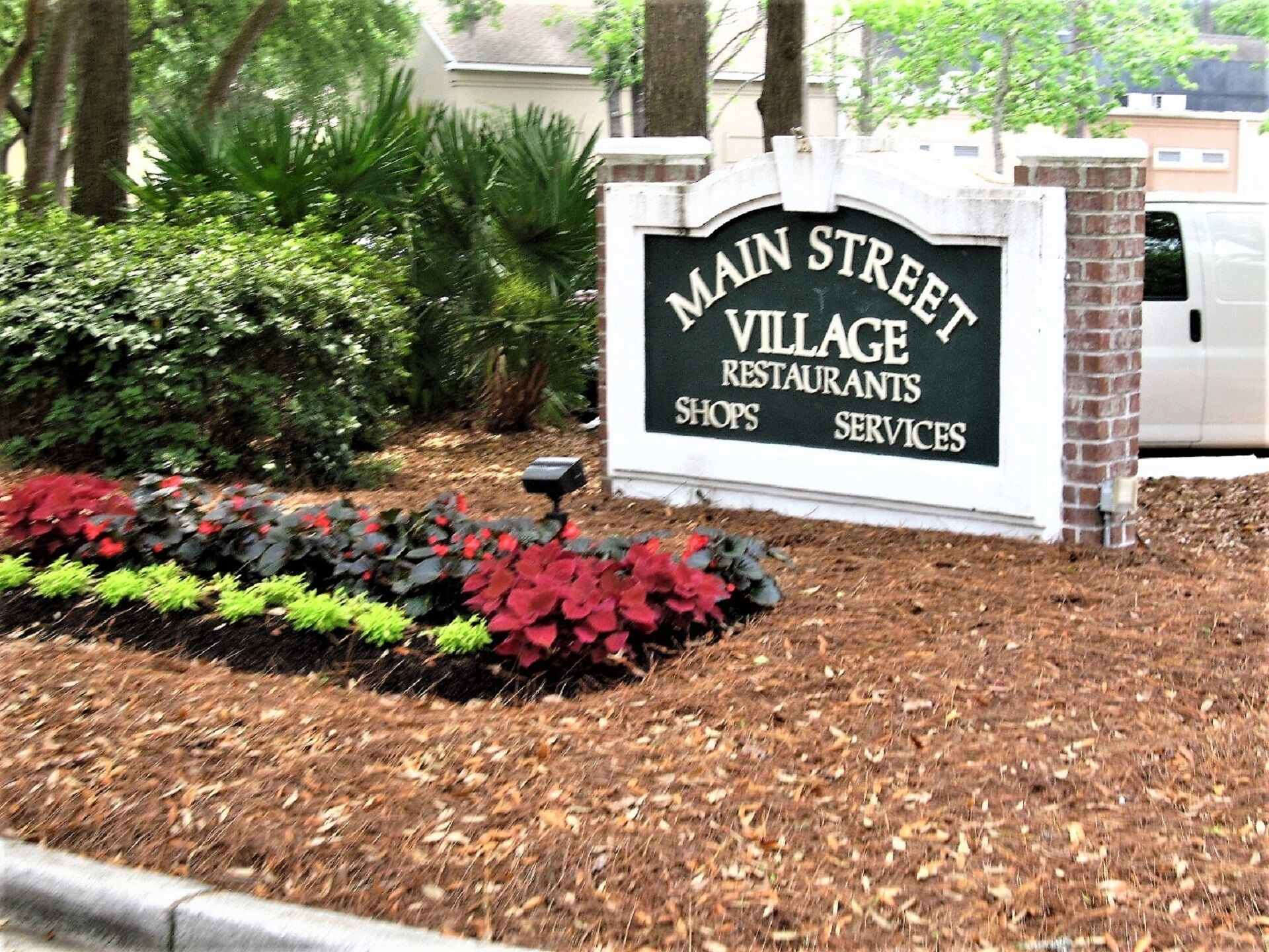 A sign for Main Street Village with a brick base and a black background.