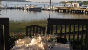 A table set for dining with a view of a marina and boats. - SUPER VALUE VACATION HOUSE: PRIVATE BEACH, GOLF, POOL, BIKES
 (Hilton Head)