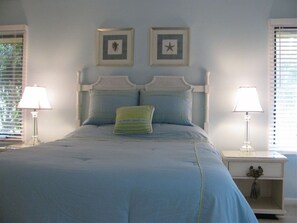 A bedroom with a bed, two bedside tables, and two wall-mounted picture frames. - SUPER VALUE VACATION HOUSE: PRIVATE BEACH, GOLF, POOL, BIKES
 (Hilton Head)