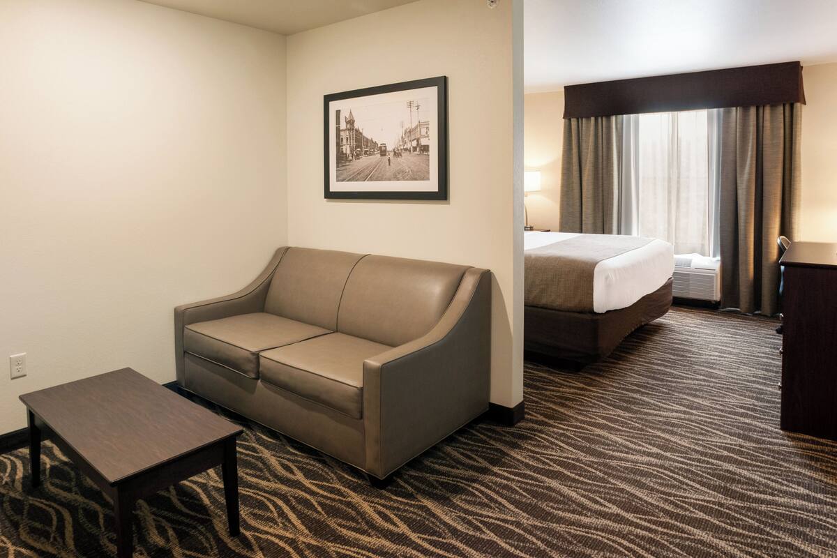 Une chambre d’hôtel avec un canapé, une petite table, un lit et un tableau encadré au mur.