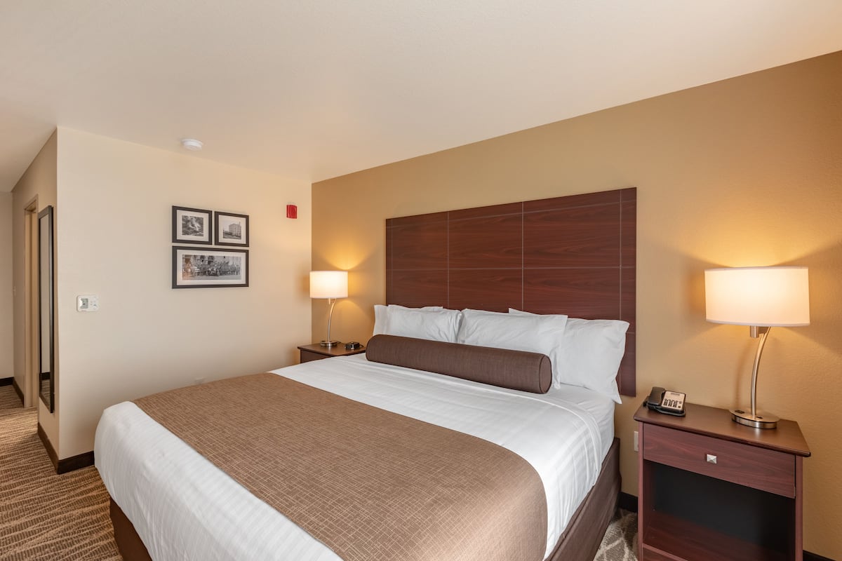 A hotel room with a large bed, two bedside tables with lamps, and framed pictures on the wall.