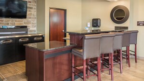 A bar area with a wooden counter, bar stools, a television, and a sign indicating breakfast is available for 40. - Cobblestone Inn & Suites - Ashland (Ashland)