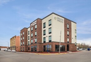 Edificio de Cobblestone Inn & Suites con fachada de ladrillo, ventanas grandes y una bandera estadounidense.