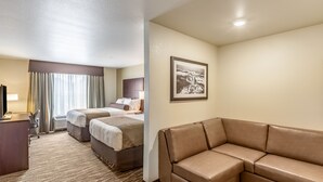 A hotel room with a large bed, a sofa, a desk, and a framed picture on the wall. - Cobblestone Inn & Suites - Ashland (Ashland)