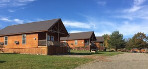 A row of wooden cabins with attached porches and a gravel driveway.