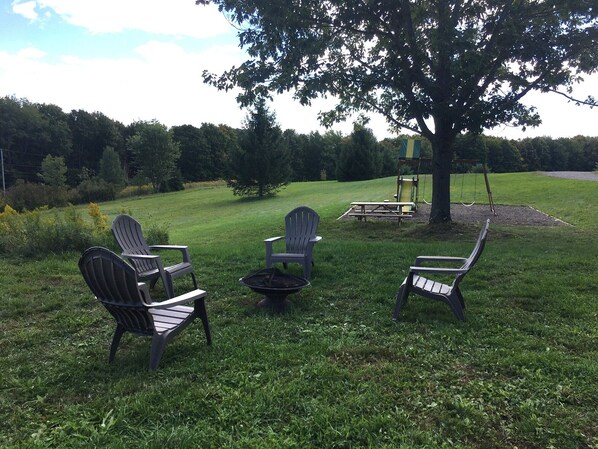 An outdoor seating area with Adirondack chairs and a fire pit.