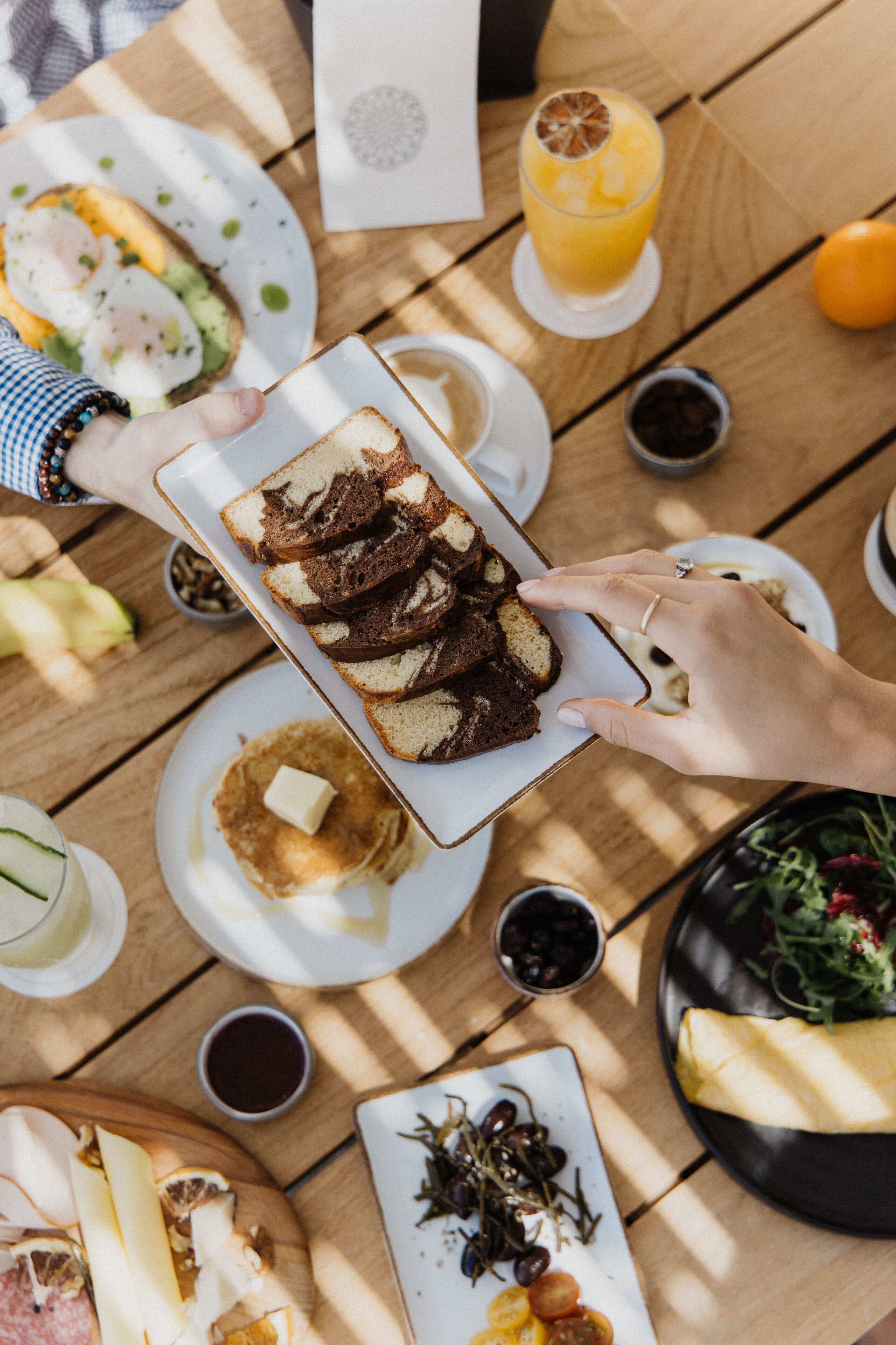 A wooden table with various dishes including toast, a plate with a poached egg, and a glass of orange juice.