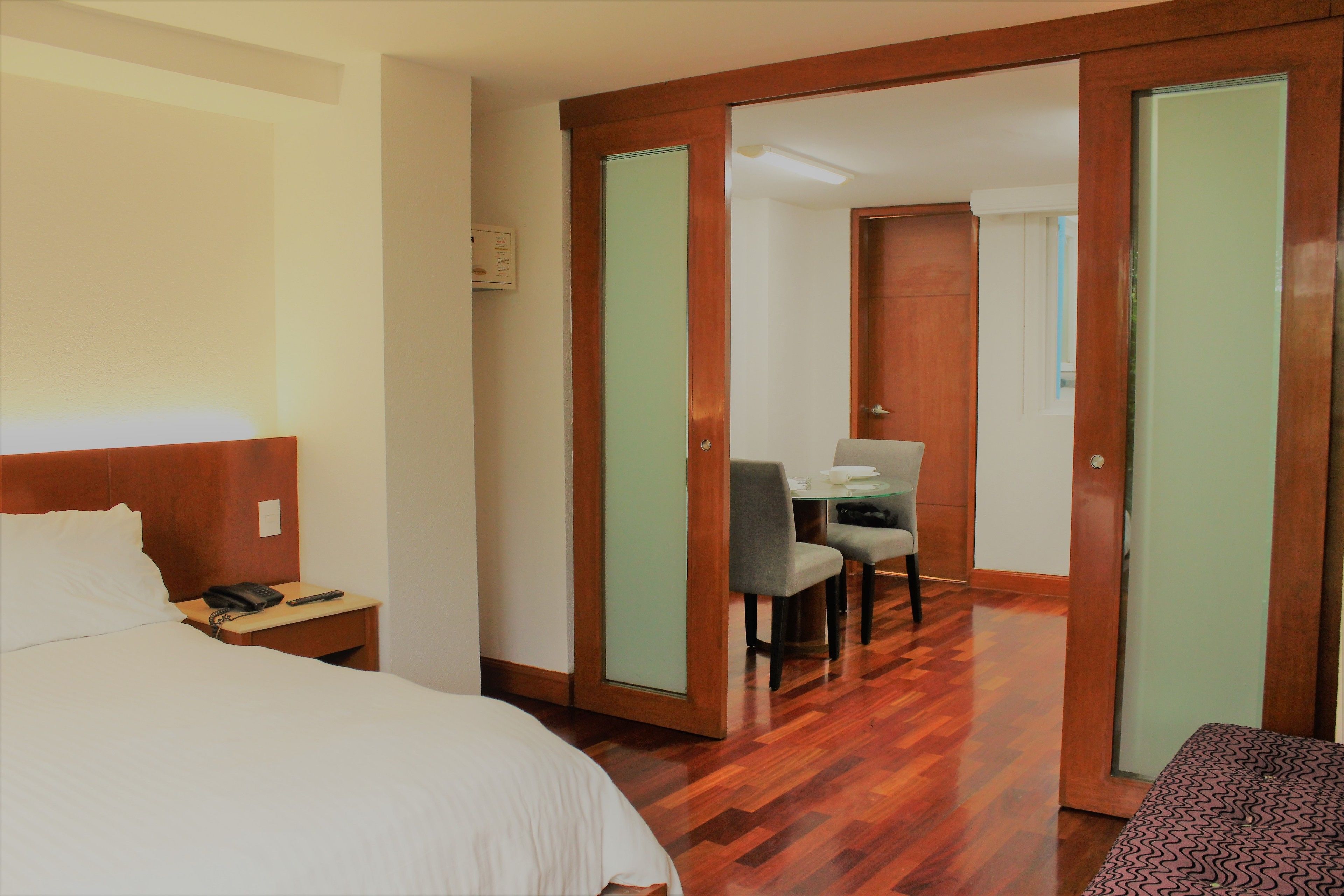 A hotel room with a bed, a desk, a chair, and a wardrobe.