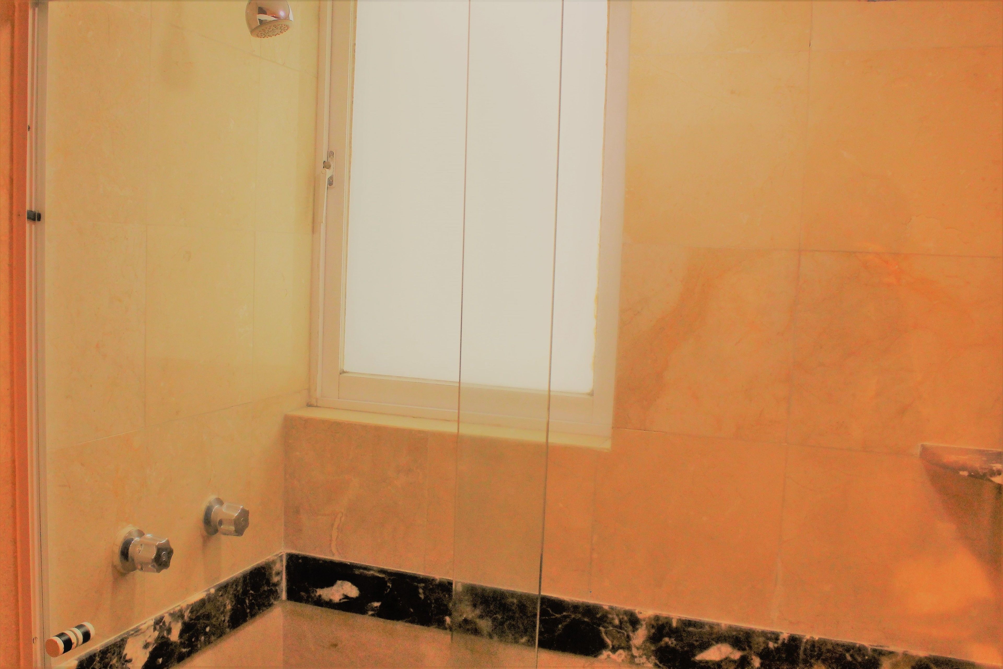 A bathroom with a large window, a shower, and a marble countertop.