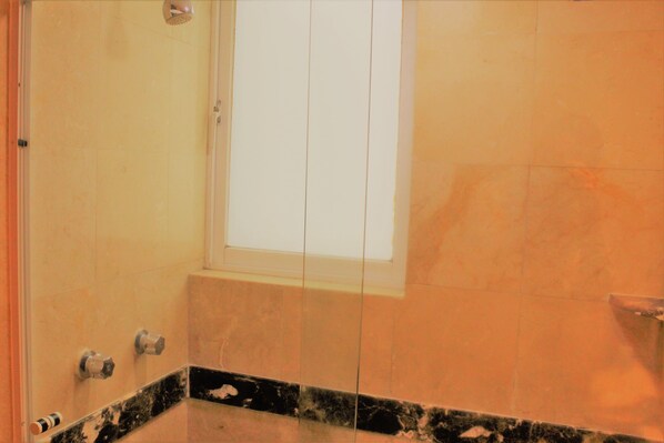 Un baño con una ventana grande, ducha y encimera de mármol.