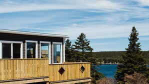 A wooden deck with a view of the ocean and trees. - Whale House Guest House (Mobile)