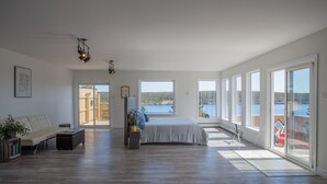 A spacious bedroom with a large bed, a sofa, and a view of a lake. - Whale House Guest House (Mobile)