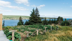 A garden with vegetable plots and wooden signs, a wooden deck, and a lake view. - Whale House Guest House (Mobile)
