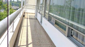 A corridor with large windows, a metal railing, and a tiled floor.