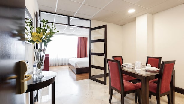 A hotel room with a dining area, a bed, and a view of the outside.