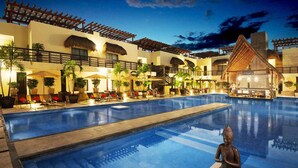 A pool area with a statue, lounge chairs, and a bar area.