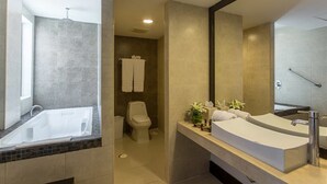 A modern bathroom with a large bathtub, a double sink vanity, and a toilet.