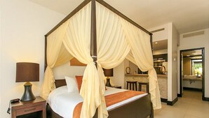 A four-poster bed with a canopy, a bedside table with a lamp, and a view of a bathroom and kitchen area. - Aldea Thai 35 by Tripintravel (Playa del Carmen)