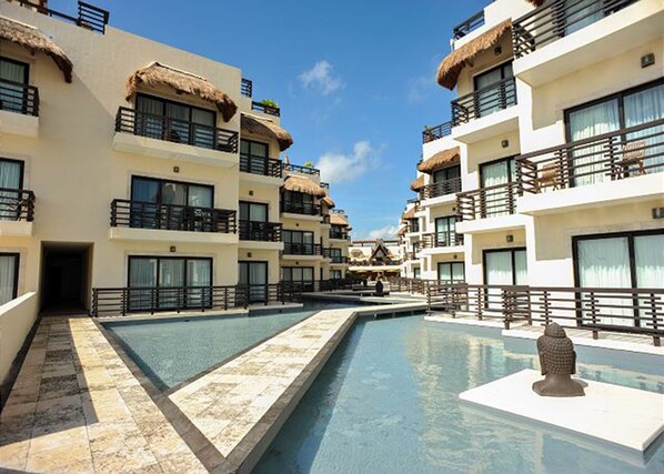 A resort with multiple-story buildings, a central swimming pool, and a Buddha statue. - Aldea Thai 01 by Tripintravel (Playa del Carmen)