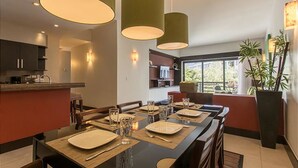 A modern dining area with a long table set for four, overhead pendant lighting, and a view of the outdoors through a large window. - Aldea Thai 27 by Tripintravel (Playa del Carmen)