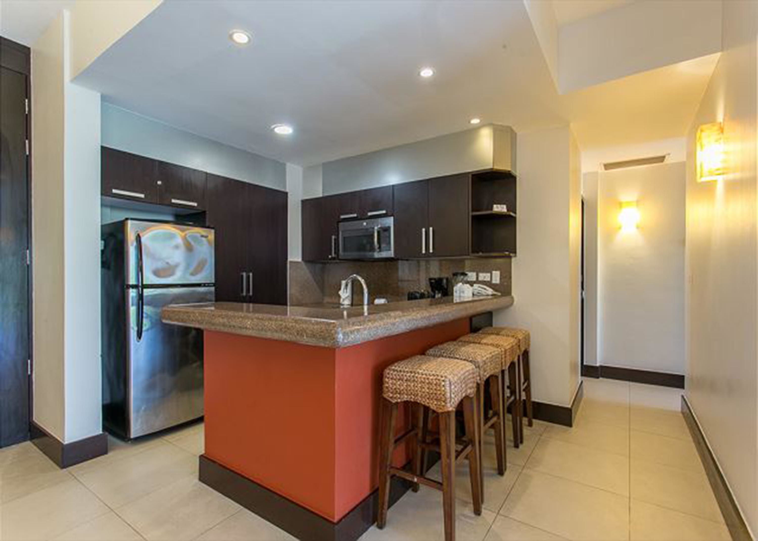 A modern kitchen with a central island, stainless steel appliances, and bar stools.