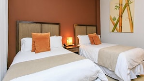 A hotel room with two beds, each with white linens and orange pillows, a nightstand with a lamp, and a wall painting of bamboo. - Aldea Thai 12 by Tripintravel (Playa del Carmen)