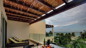 A balcony with a glass table, wicker chairs, and a view of the beach. - Elements PH20 by Tripintravel (Playa del Carmen)