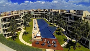 A modern hotel with multiple floors, a central swimming pool, and outdoor seating areas.