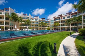 A hotel with a swimming pool, palm trees, and a clear blue sky. - Elements GH09 by Tripintravel (Playa del Carmen)