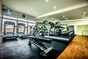 Een fitnessruimte met loopbanden, elliptische trainers en gewichten.