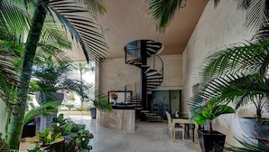 A spacious interior with a central spiral staircase, surrounded by lush tropical plants.