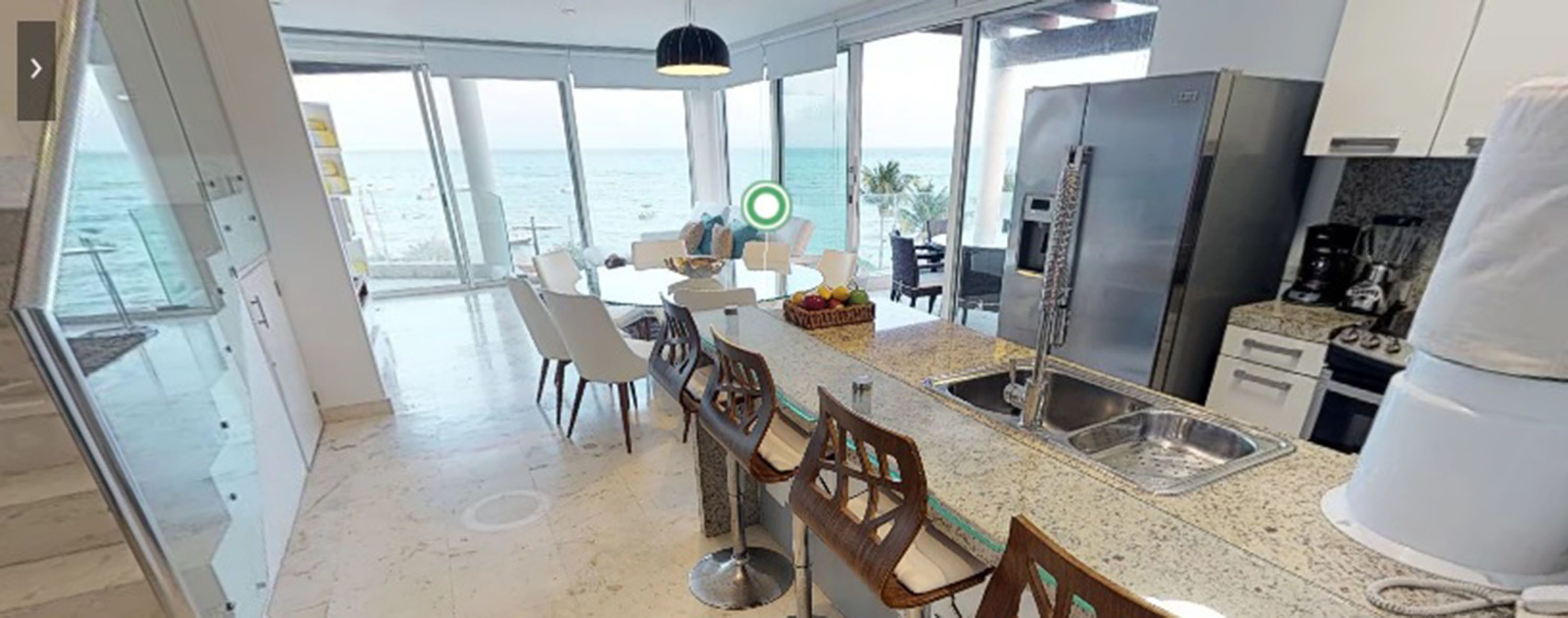 Una cocina moderna con una isla grande, electrodomésticos de acero inoxidable y vistas al océano.