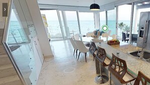 Een moderne keuken met een groot eiland, roestvrijstalen apparatuur en uitzicht op de oceaan.