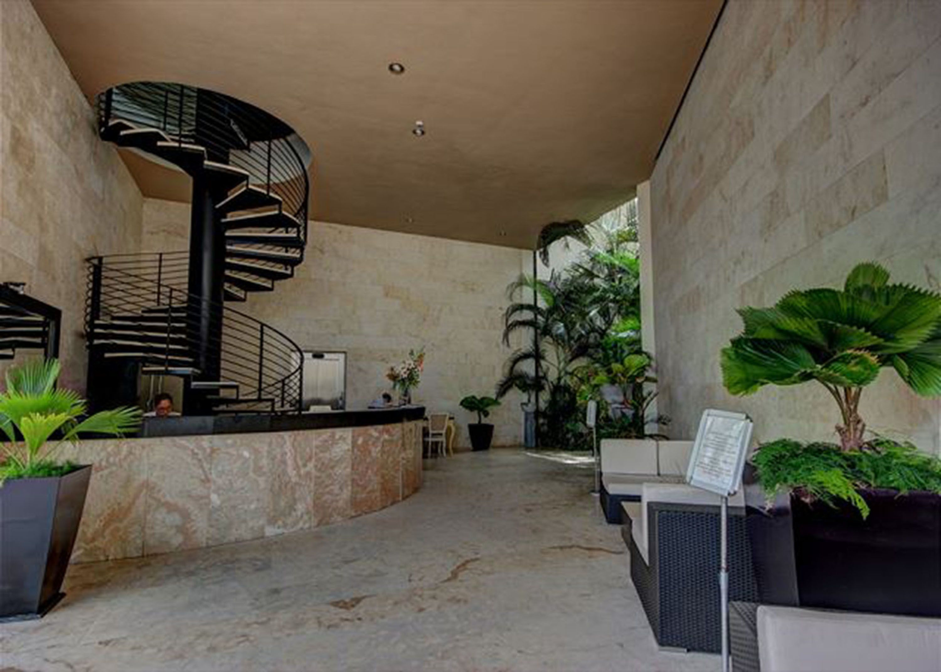 A modern lobby with a spiral staircase, seating area, and potted plants.