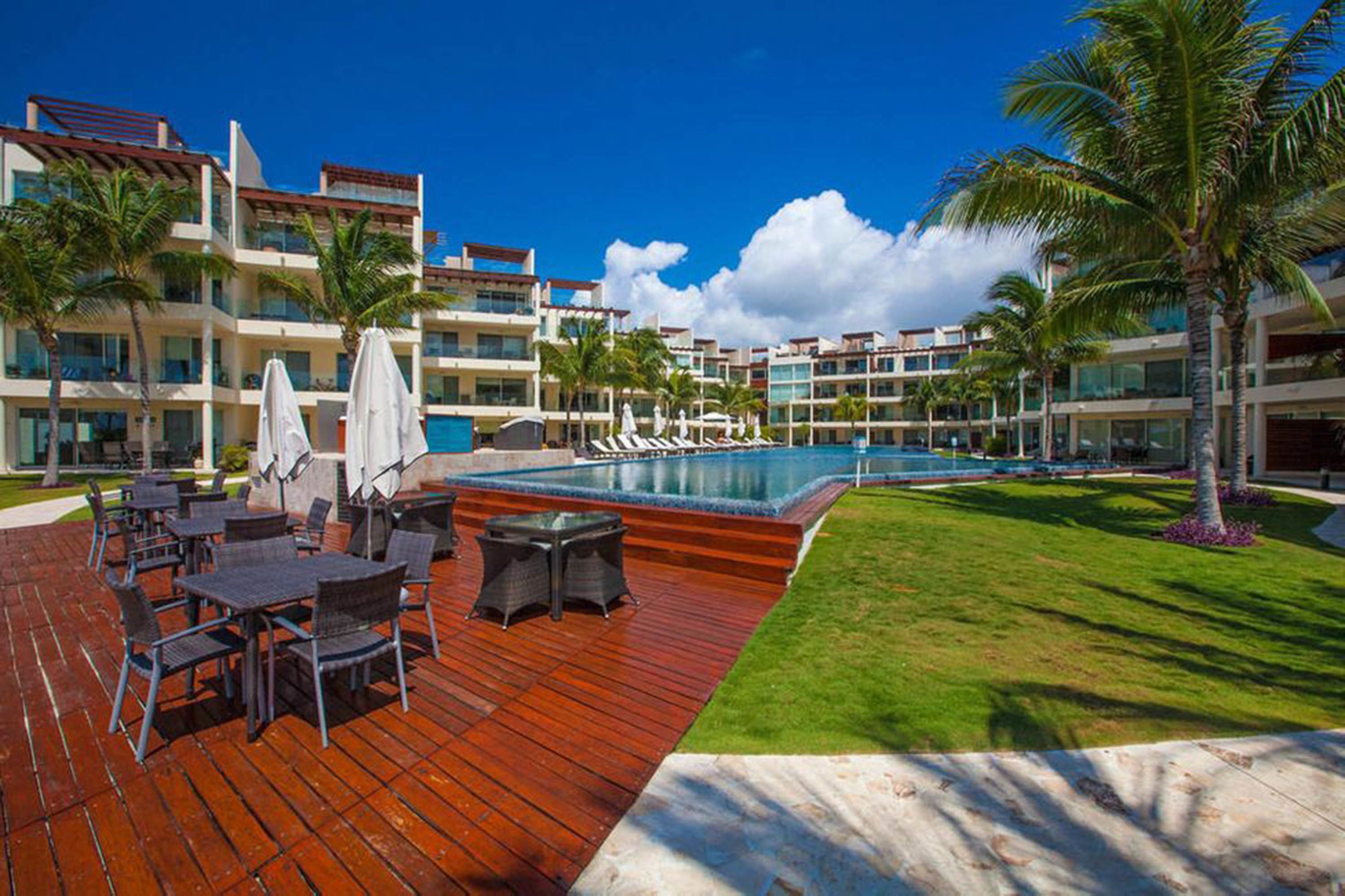 A resort with a swimming pool, outdoor seating, and palm trees.