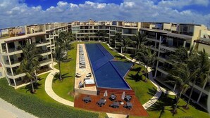 A modern hotel with multiple floors, a central swimming pool, and outdoor seating areas. - Elements 206 by Tripintravel (Playa del Carmen)
