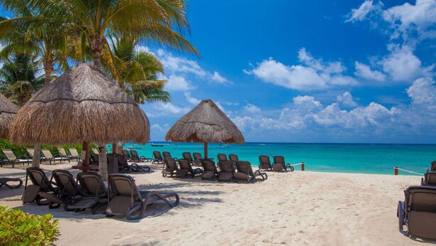 A beach with thatched umbrellas, lounge chairs, and a clear view of the ocean. - Elements 206 by Tripintravel (Playa del Carmen)