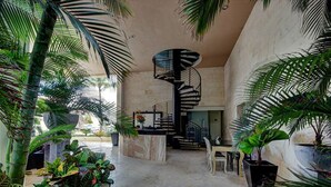 A spacious interior with a central spiral staircase, surrounded by lush tropical plants. - Elements 206 by Tripintravel (Playa del Carmen)