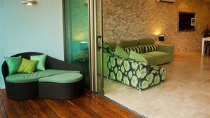 A modern living room with a glass door leading to a balcony, a green sofa, and a patterned ottoman. - DOCA 201 by Tripintravel (Playa del Carmen)