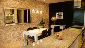 A modern kitchen with a granite countertop, a dining area with chairs, a large window, and pendant lights. - DOCA 201 by Tripintravel (Playa del Carmen)