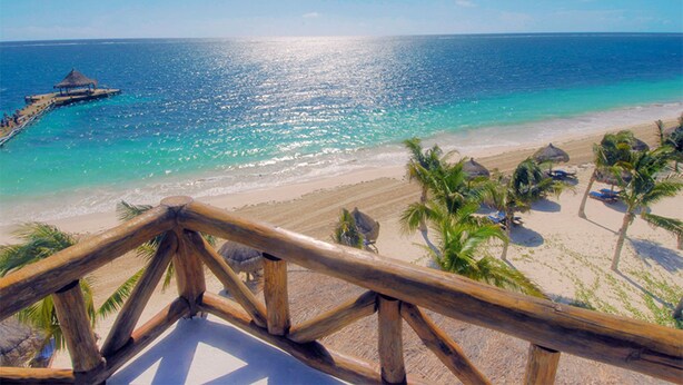 A beach view with a wooden railing, clear turquoise water, and a thatched structure on the left. - DOCA 201 by Tripintravel (Playa del Carmen)