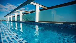 A swimming pool with clear blue water, surrounded by glass walls and supported by white pillars. - DOCA 201 by Tripintravel (Playa del Carmen)