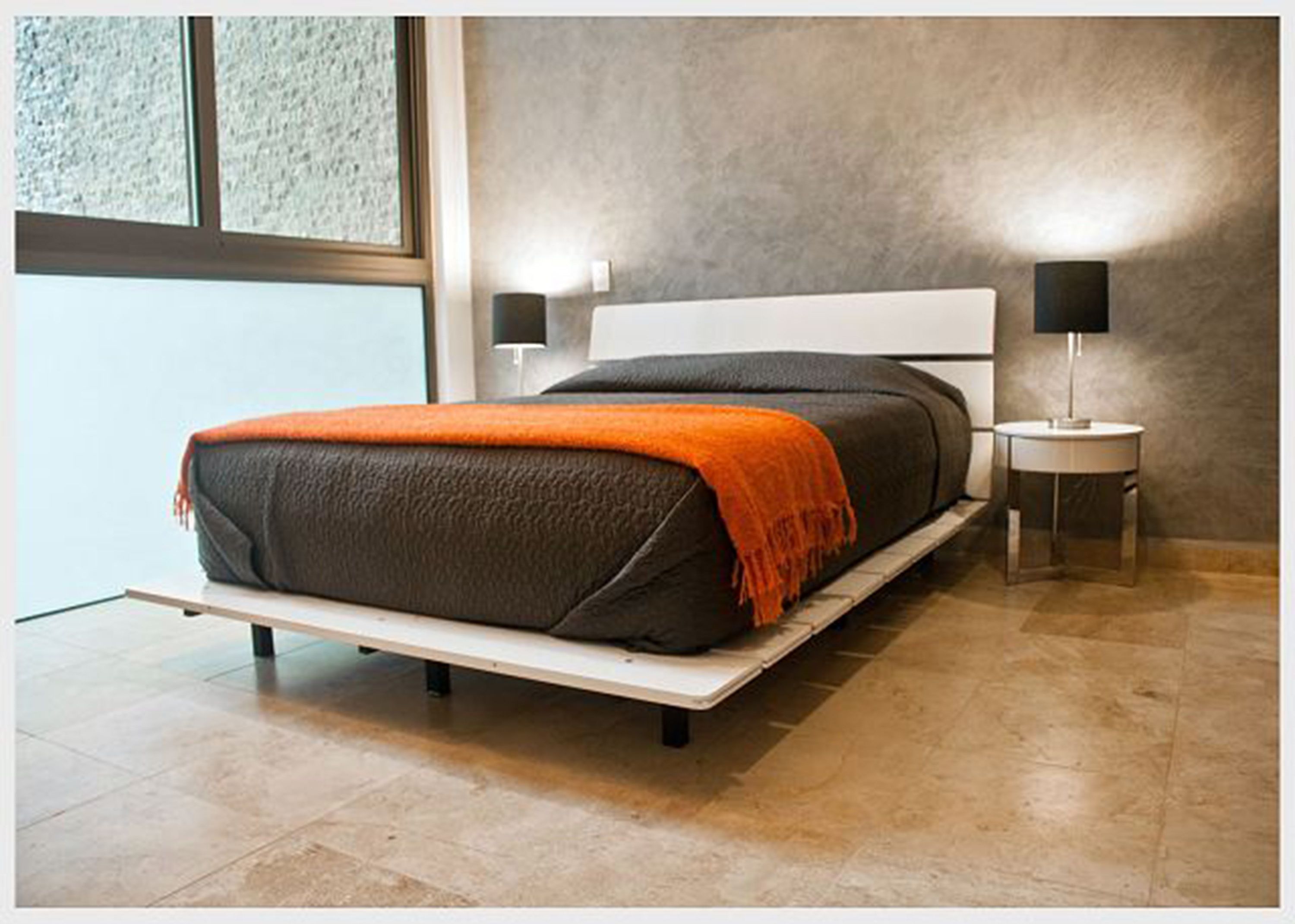 A modern bedroom with a bed, two bedside tables, and a window.