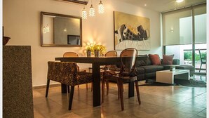 A modern dining area with a wooden table and chairs, a large mirror, and a contemporary painting.