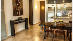 A modern dining area with a large table, chairs, and a console table with a painting.