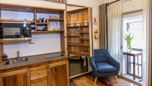 Una cucina compatta con forno a microonde integrato, mobili in legno e un piccolo lavandino.